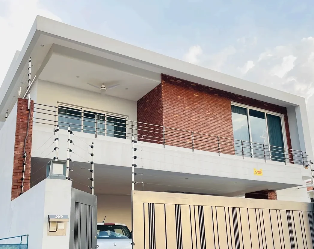 Modern 1 Kanal house exterior in DHA 5 Islamabad featuring exposed red brickwork and minimalist white cubic design by Babar Malik Architects.