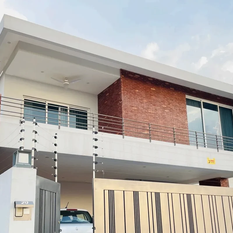 Modern 1 Kanal house exterior in DHA 5 Islamabad featuring exposed red brickwork and minimalist white cubic design by Babar Malik Architects.