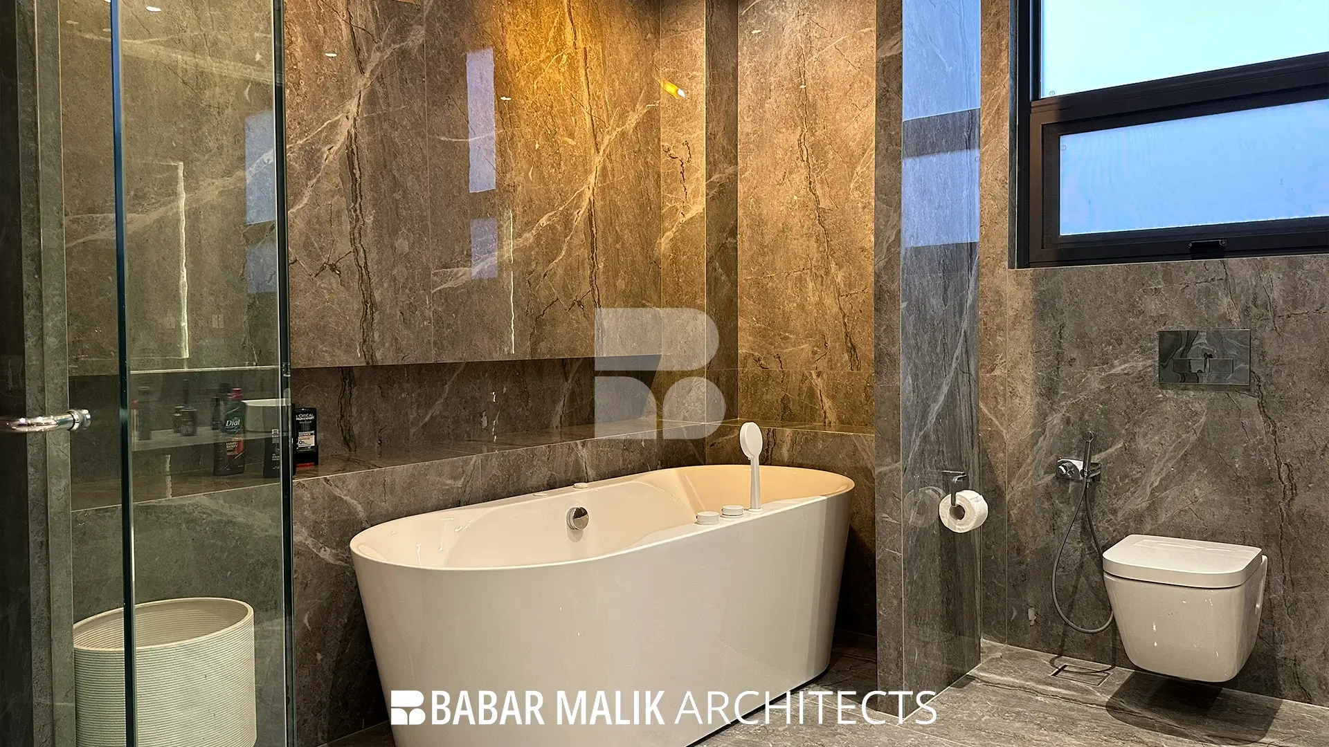 Detailed view of a white freestanding bathtub positioned against a grey marble wall in the master bathroom.